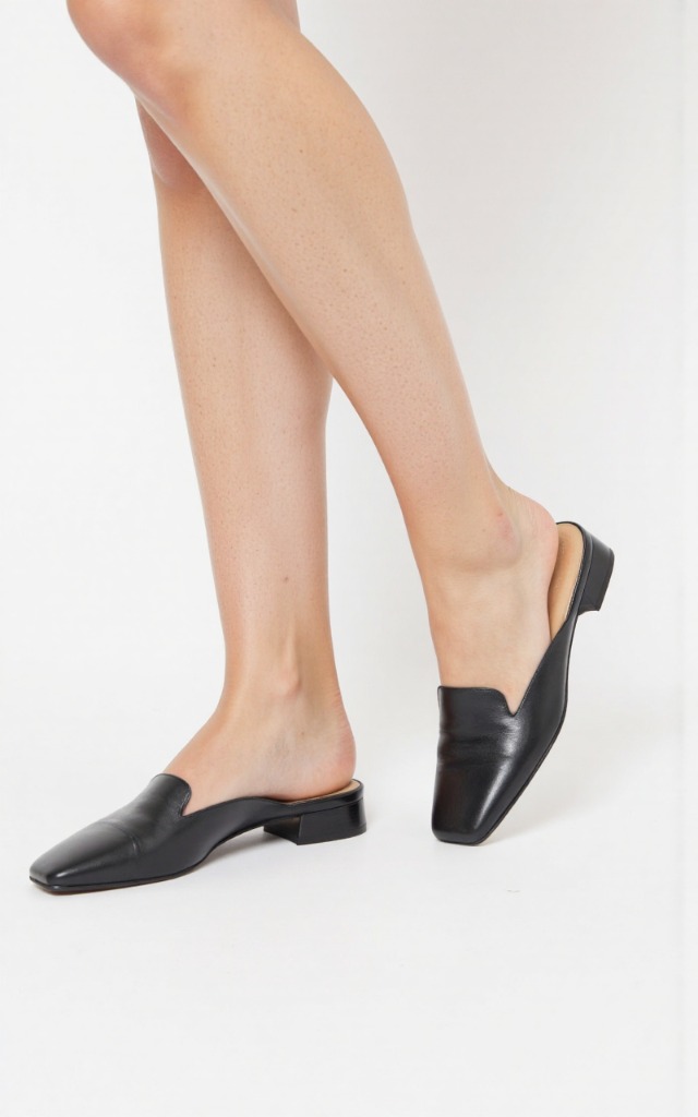 A female model wearing square   toe shoes, against a white background, with a close   up of the feet